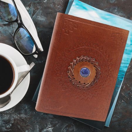 lined notebook with brown leather cover and lapis lazuli hand stitched into centre
