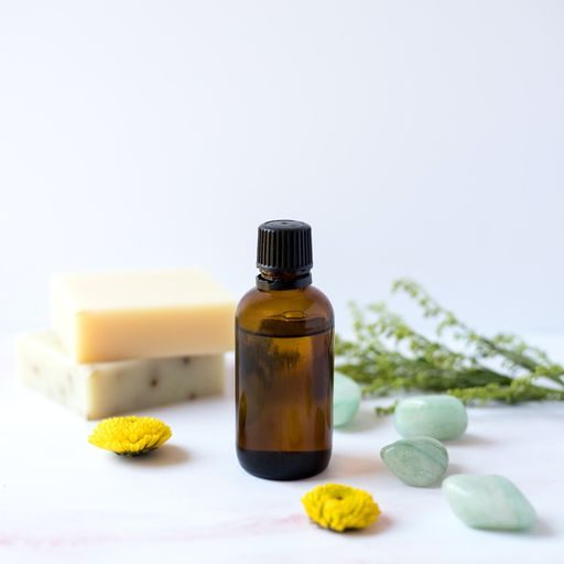 A brown glass bottle of essential oils with soap and gemstones